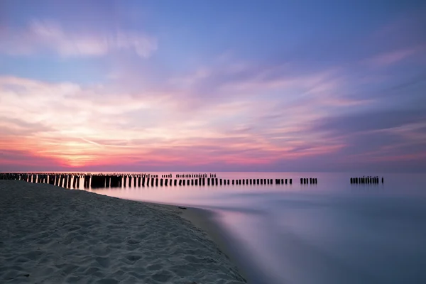 Sunset a vlnolamů na pobřeží Baltského moře. Dlouhé expozice — Stock fotografie