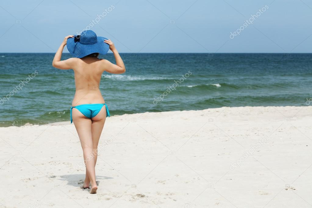 Woman in hat on the beach with her back