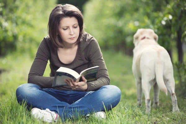 Kobieta czytająca książkę w sadzie — Zdjęcie stockowe