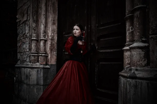 Mysterious woman in red Victorian dress with a candle — Stock Photo, Image