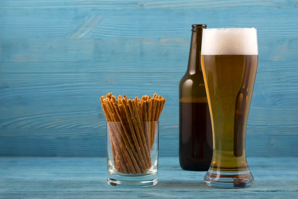 Beer and salty sticks on a blue background — Stock Photo, Image
