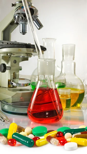 Varia laboratório de vidro, microscópio e comprimidos close-up — Fotografia de Stock