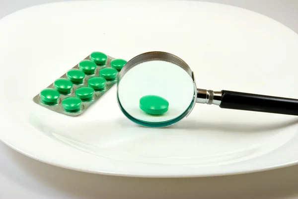 Isolated image of a tablet and a magnifying-glass on a plate — Stock Photo, Image