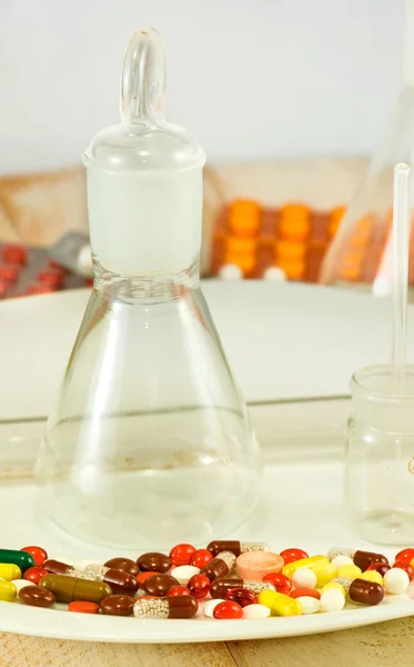 Image of pills on a plate, vial and flasks — Stock Photo, Image