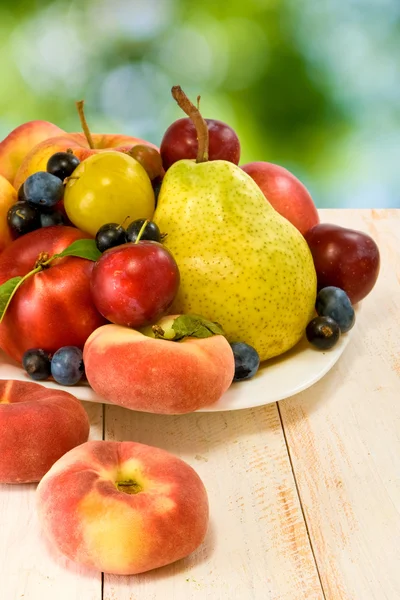 Various fruits on a table on green background — Stock Photo, Image