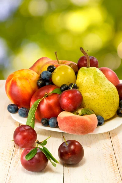 Różne owoce na stole na tło zamazane pole — Zdjęcie stockowe