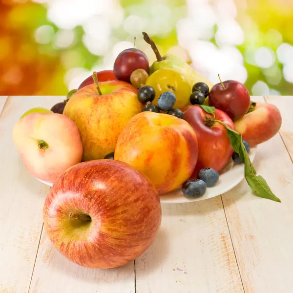 Various ripe fruits on a plate on a blurred background — Stock Photo, Image
