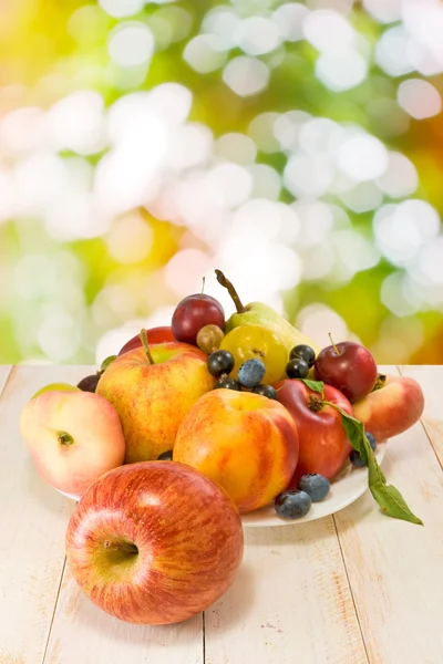 Different fruits on a plate on a blurred background — Stock Photo, Image