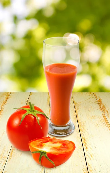 Изображение помидоров и стакан сока на зеленом фоне — стоковое фото