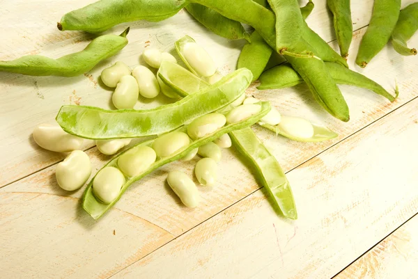 Afbeelding van bonen in peulen op een houten tafel — Stockfoto