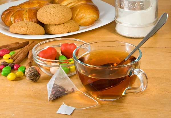 Bild einer Tasse Tee, Kuchen und Brötchen auf dem Tisch — Stockfoto