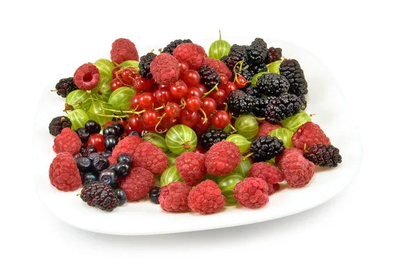 Различные ягоды в тарелке на белом фоне — стоковое фото
