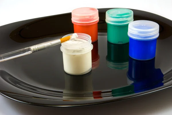 Isolated image of different paints and brush on a black plate — Stock Photo, Image