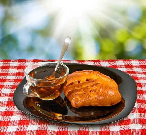 Kopje thee en broodjes op een tafel tegen de zon — Stockfoto