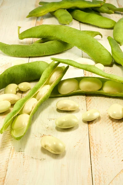 Beans in pods on a wooden table — Stock Photo, Image