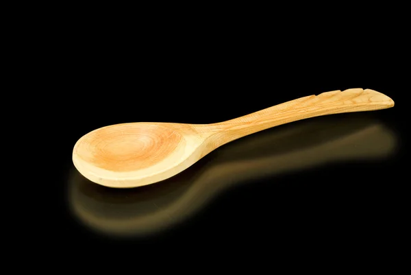 Wooden spoon on a black background closeup — Stock Photo, Image