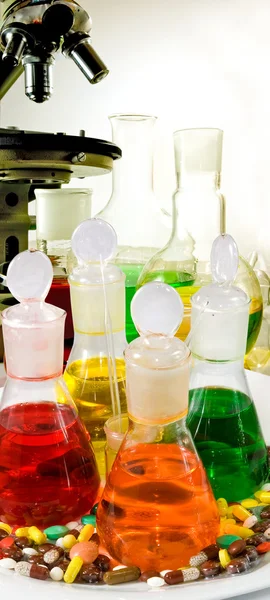 Химические колбы, микроскоп и таблетки крупным планом — стоковое фото