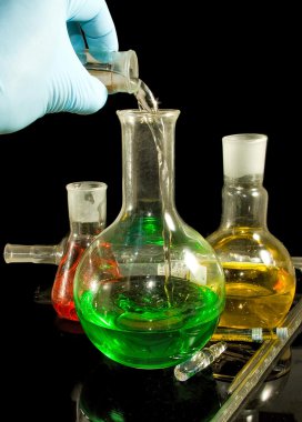  bir elinde bir siyah arka plan portre üzerinde bir eldiven ve laboratuvar cam ürünleri