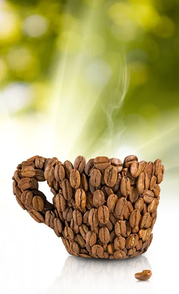 Uma xícara decorada com grãos de café em um fundo verde — Fotografia de Stock