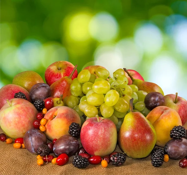 Many fruits and berries on a green background — Stock Photo, Image