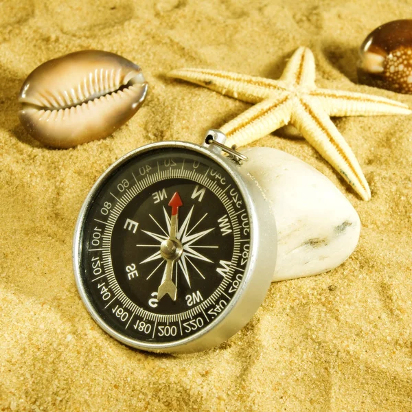 Conchas do mar e bússola na areia closeup — Fotografia de Stock