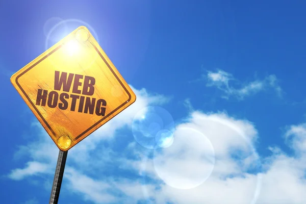 Yellow road sign with a blue sky and white clouds: web hosting — Stockfoto