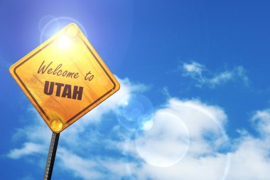 Yellow road sign with a blue sky and white clouds: Welcome to ut