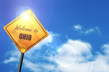 Yellow road sign with a blue sky and white clouds: Welcome to oh