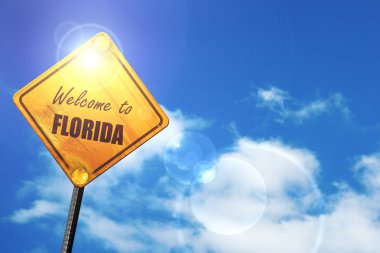 Yellow road sign with a blue sky and white clouds: Welcome to fl