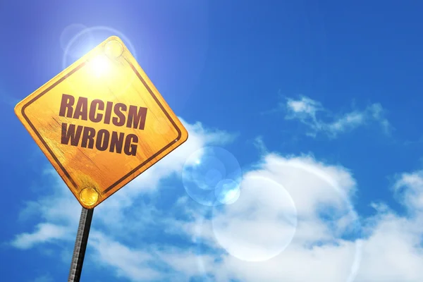 Sinal de estrada amarelo com um céu azul e nuvens brancas: racismo errado — Fotografia de Stock