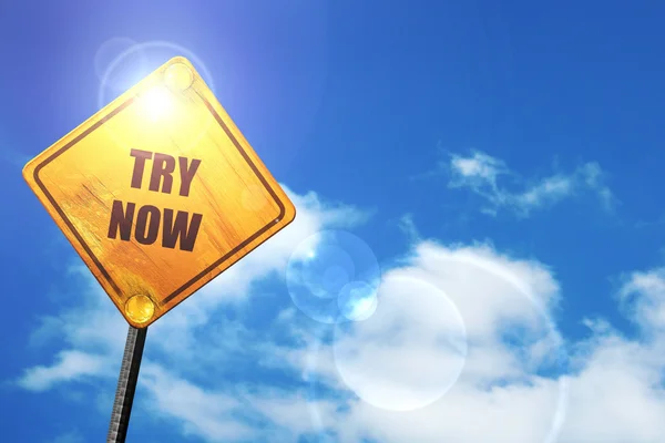 Yellow road sign with a blue sky and white clouds: try now sign — Stockfoto