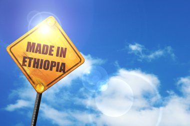 Yellow road sign with a blue sky and white clouds: Made in ethio