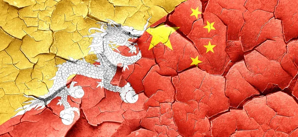 Bhútán vlajky s příznakem Čína na to grunge popraskané zdi — Stock fotografie