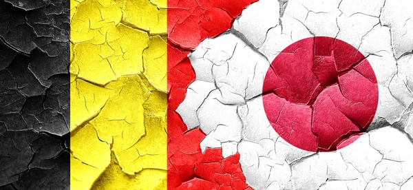 Belgien flagga med Japan flagga på en grunge knäckt vägg — Stockfoto