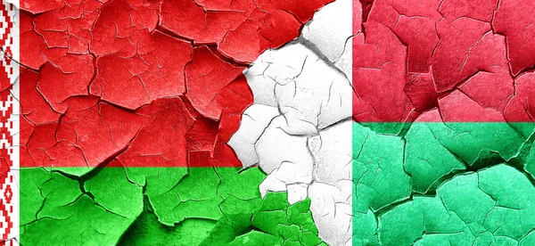 Belarus flag with Madagascar flag on a grunge cracked wall