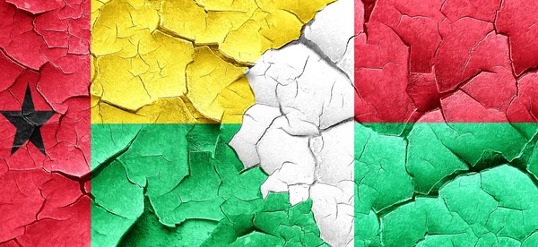 Γουινέα Μπισσάου σημαία με τη σημαία της Μαδαγασκάρης σε μια grunge ραγισμένα τοίχο — Φωτογραφία Αρχείου