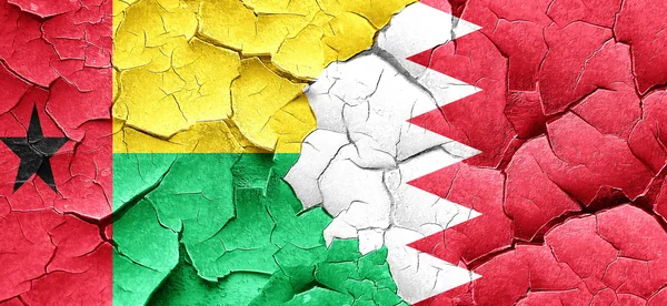 Guinea-Bissau-Flagge mit Bahrain-Flagge an einer Grunge-Risswand — Stockfoto