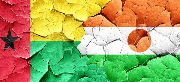 Guinea-Bissau-Flagge mit Nigerfahne an einer Grunge-Risswand — Stockfoto