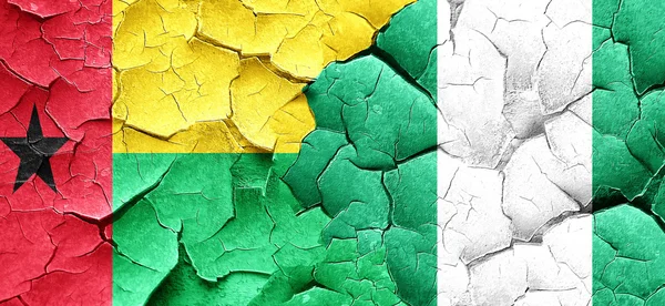 Guinea-Bissau-Flagge mit Nigerfahne an einer Grunge-Risswand — Stockfoto