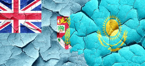 Fiji flag with Kazakhstan flag on a grunge cracked wall