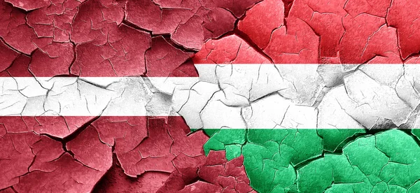 Latvia flag with Hungary flag on a grunge cracked wall