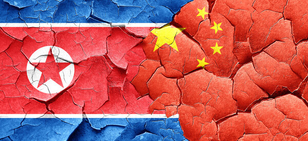 North Korea flag with China flag on a grunge cracked wall
