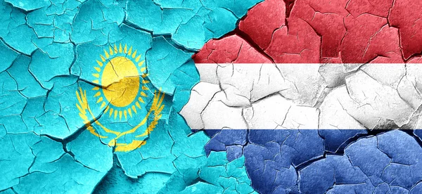 Kazakhstan flag with Netherlands flag on a grunge cracked wall