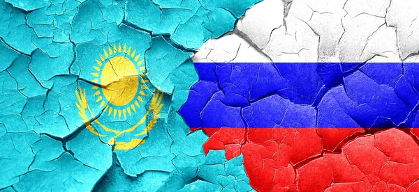 Kazakhstan flag with Russia flag on a grunge cracked wall