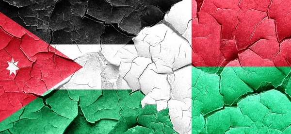 Bandera de Jordania con bandera de Madagascar en una pared agrietada grunge — Foto de Stock