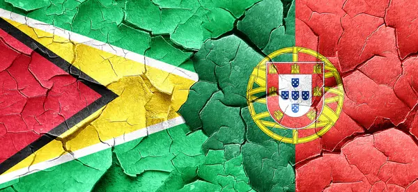Guyana-Flagge mit portugiesischer Flagge an einer Grunge-Risswand — Stockfoto