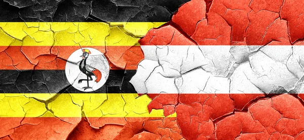 Flaga Ugandy z flaga Austrii na grunge popękane ściany — Zdjęcie stockowe