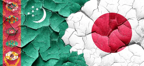 Turkmenistan flag with Japan flag on a grunge cracked wall