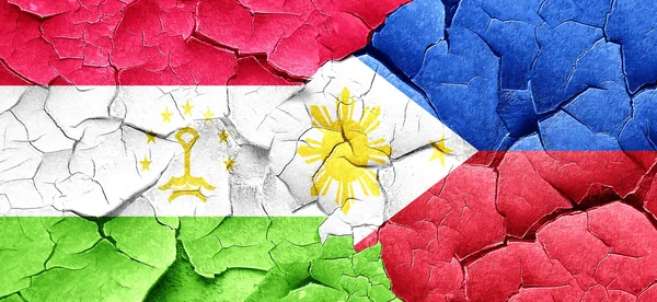 Tajikistan flag with Philippines flag on a grunge cracked wall