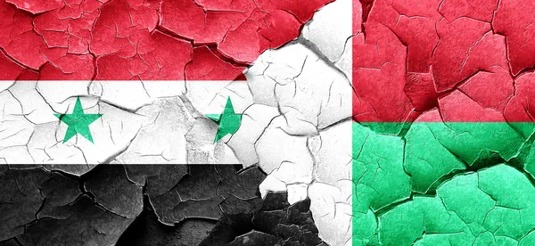 Syrien flagga med Madagaskar flagga på en grunge knäckt vägg — Stockfoto